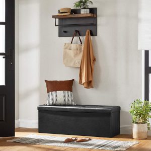 Modern entryway with a black storage bench, decorative pillow, hanging coat rack with shelf, and a potted plant.