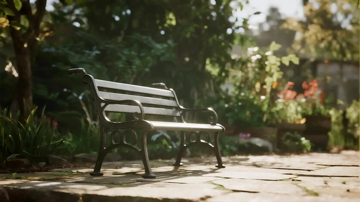 A black metal bench on a stone path, surrounded by lush greenery and colorful flowers, bathed in warm sunlight.