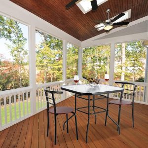 Cozy outdoor patio with a table set for two, featuring a glass-top square table, two metal chairs, and wine glasses.