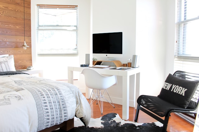 Bright and modern bedroom workspace with an iMac on a white desk, an ergonomic chair, and New York-themed decor.