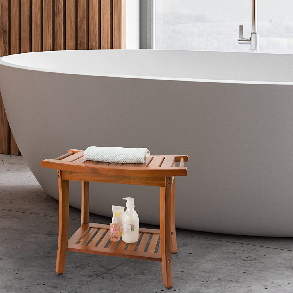 A wooden bath stool placed in front of a modern freestanding bathtub, with a towel and bath products on the stool.